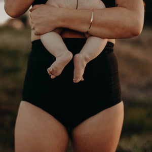 New Mum wearing high waist postpartum underwear holding a newborn baby.
