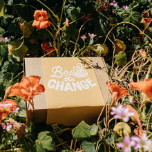 Load image into Gallery viewer, Bee the Change Seed Gift Box in a garden bed.