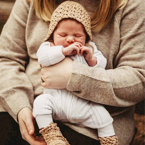 mum-holding-baby-dressed-in-knitted-bonnet-and-booties