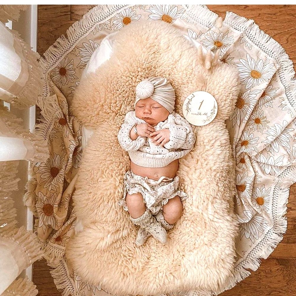 newborn baby lying on a sheepskin rug and daisy blanket