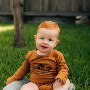 ginger haired baby sitting outside in the grass
